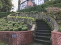 Stone stairway winds up along brick and stone walls past sculpted shrubbery in Portland, Oregon