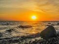 A stone standing near the shore of lake at sunrise