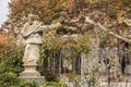 Stone statue with colored leaves of a tree and ivy