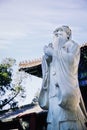 Stone statue of Confucius, traditional pagoda in the background