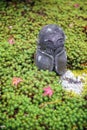 Stone statue of Jizo on ground covered by green star moss and red maple leaves during autumn in a garden at Enkoji temple in Kyoto Royalty Free Stock Photo