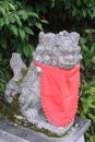Stone statue of komainu lion-dog with a red bib in front of a shinto shrine in Japan