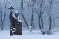 Stone statue of a bishop in snowy forest scenery, monochrome image