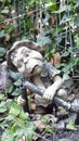 Stone statue of a troll standing in the border of the garden