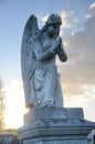 A stone statue of a winged angel at sunset