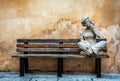 Stone statue of a youngster sitting and listening to music on a wooden bench