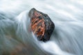 Stone in a stream with water blurred by long exposure Royalty Free Stock Photo