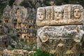 Stone theater faces and masks in Myra Ancient City. Lycian rock tombs in background. Demre, Antalya Royalty Free Stock Photo