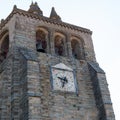 Stone tower with three bells and a beautiful ancient clock. Evora, Portugal, Royalty Free Stock Photo