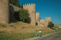 Stone towers on the large city wall and pedestrians at Avila