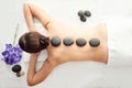 Stone treatment. Top view of beautiful young woman lying on front with spa stones on her back. Beauty treatment concept. Royalty Free Stock Photo