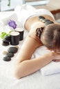 Stone treatment. Top view of beautiful young woman lying on front with spa stones on her back. Beauty treatment concept. Royalty Free Stock Photo