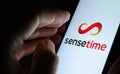 SenseTime artificial intelligence SaaS company logo on the glowing screen and a hand touching it. Concept photo