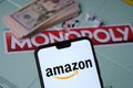 Amazon logo on smartphone placed next to Monopoly game with real money. Conceptual photo