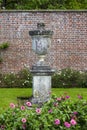 Stone urn in green lawn against red brick wall