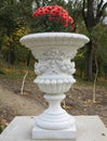 Stone vase in the old classical style with flowers in the park