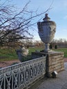 Stone vases of the Elaginoostrovsky Palace with a beautiful fence against the background of leafless trees, meadows, rivers and
