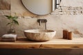 Stone vessel sink with mirror against textured stone wall in minimal bathroom in natural earth tones