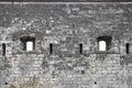 Stone wall of an ancient castle with windows in the form of loopholes. Close-up. Selective focus