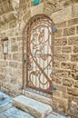 Stone wall. a beautiful door with a pattern behind an iron grating. Israel Royalty Free Stock Photo