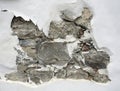Stone background in uncorked white cement wall. Hole in the concrete. Closeup of peeling painted wall. Concrete wall in cracks. Royalty Free Stock Photo