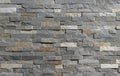 Stone wall cladding made of horizontal gray, brown and white strips of rock stacked .