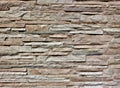 Stone wall cladding made of thin stripes natural rocks. Colors are shades of brown and gray.