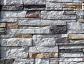 Stone wall cladding made of white stacked rocks with insert of brown and black stones.