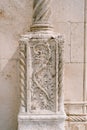 Stone wall with a flower-shaped bas-relief on a column. Royalty Free Stock Photo