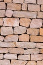 Stone wall folded from beige cobblestone uneven vertical pattern Royalty Free Stock Photo