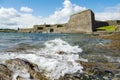 Stone wall of Fort Charles, Kinsale town, Ireland. Warm sunny day, cloudy sky. Blue ocean water. Powerful fortification to protect