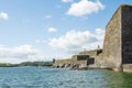 Stone wall of Fort Charles, Kinsale town, Ireland. Warm sunny day, cloudy sky. Blue ocean water. Powerful fortification to protect