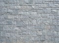 Stone wall with gray stone tiles of different dimensions and shape arranged geometrically.