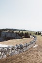 Stone wall near a cliff on a green field under a cloudy sky Royalty Free Stock Photo