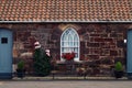 Stone wall of an old beautiful house with a tiled roof and window decorated with flowers Royalty Free Stock Photo