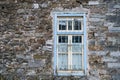 Stone wall with wooden blue framed window with complicated iron bar, Epirus Greece, winter day Royalty Free Stock Photo