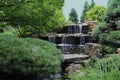 A stone waterfall cascading into a pond in a landscaped Japanese garden in Wisconsin Royalty Free Stock Photo