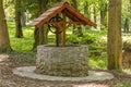 A stone well with a roof in the middle of a forest Royalty Free Stock Photo