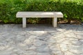 A stone white bench without a backrest in the park for rest on a stone semi-road against the background of green bushes Royalty Free Stock Photo