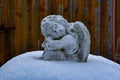 Stone white sculpture of a little angel sitting on the snow Royalty Free Stock Photo