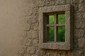 A stone window in the stone wall of an old building overlooking the greenery. Space for text. Royalty Free Stock Photo