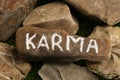 Stone with word Karma on green grass, above view