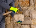 Stonecutter mason with hammer and stone working masonry