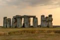 Stonehenge monoliths stand in a lush green field, with dramatic golden light radiating from the sky