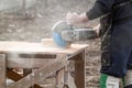 Stonemason cutting brick with diamond saw outdoors in a cloud of dust