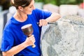 Stonemason working on boulder with sledgehammer and iron