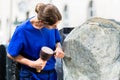 Stonemason working on boulder with sledgehammer and iron