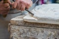 Stonemason works a white stone with hammer and chisel. Hands with tools and white stone block