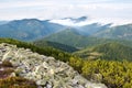 Stones against the hill covered with fluffy white clouds Royalty Free Stock Photo