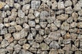 stones behind metal grate. Granite paving stone in steel container. metal mesh holds wall of stones. Royalty Free Stock Photo